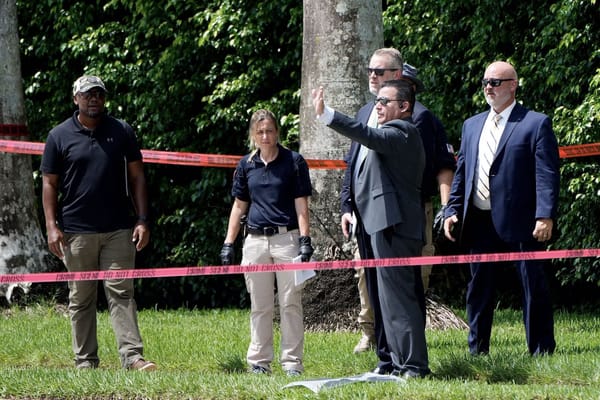 Law enforcement personnel investigate the area around Trump International Golf Club on Monday